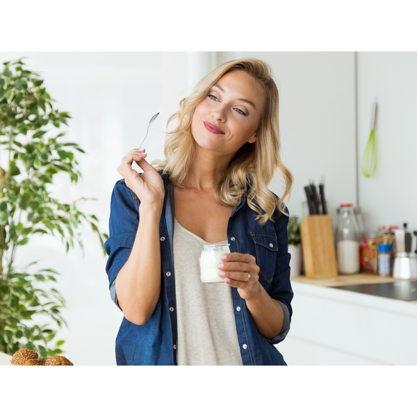 Woman holding Greek yogurt in glass, top natural probiotic fermented foods.